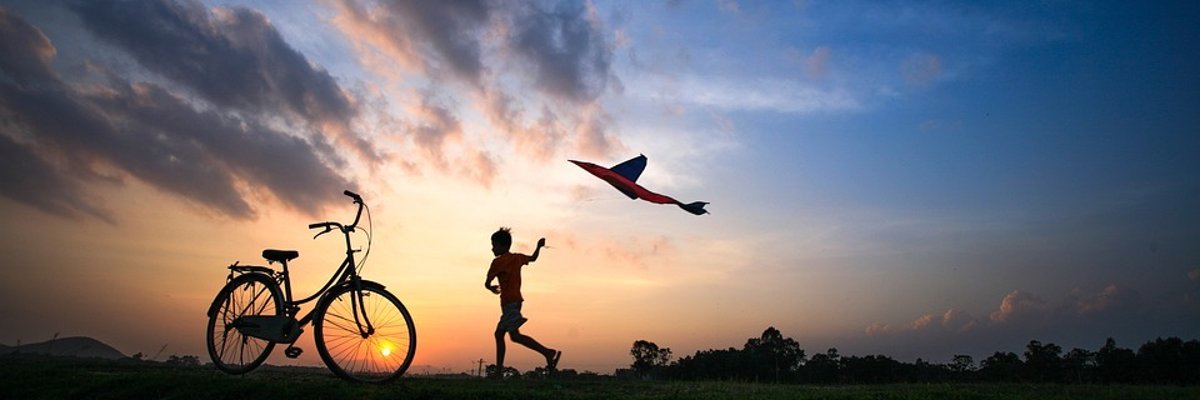 Kind im Sonnenuntergang Kind mit Drachen und Fahrrad